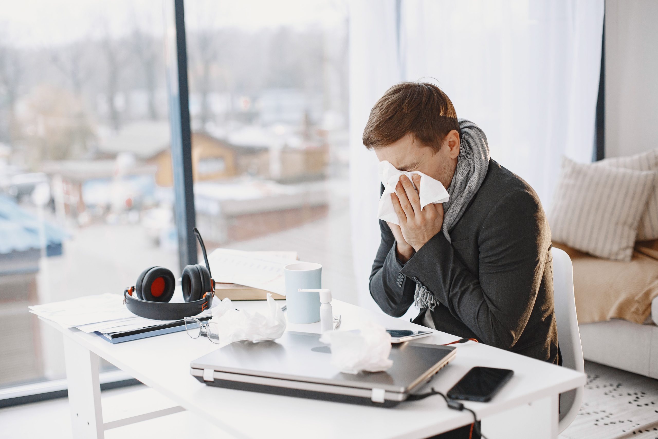 Homme éternuant au bureau pendant télétravail