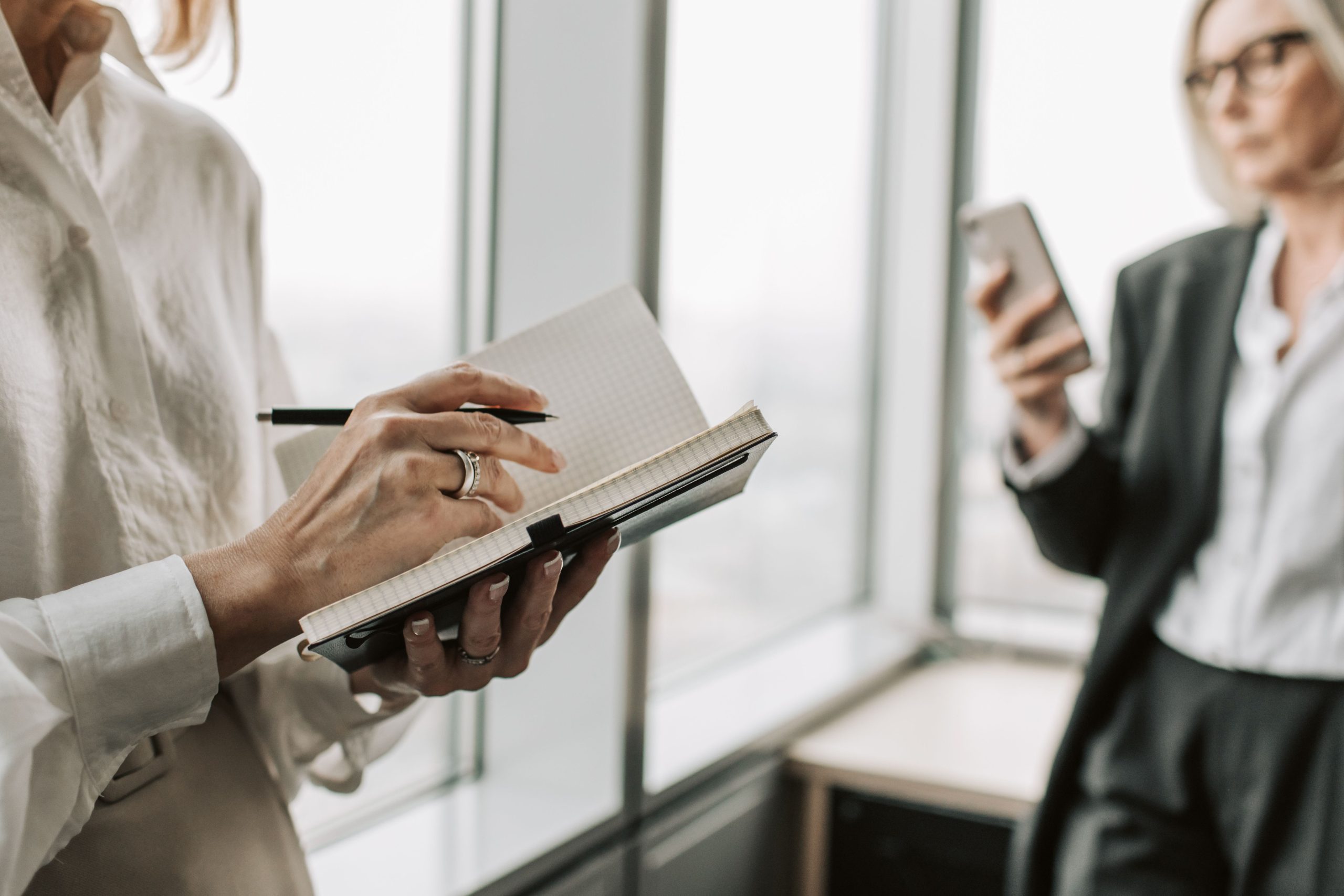 Femmes collaborant bureau notant informations sur smartphone