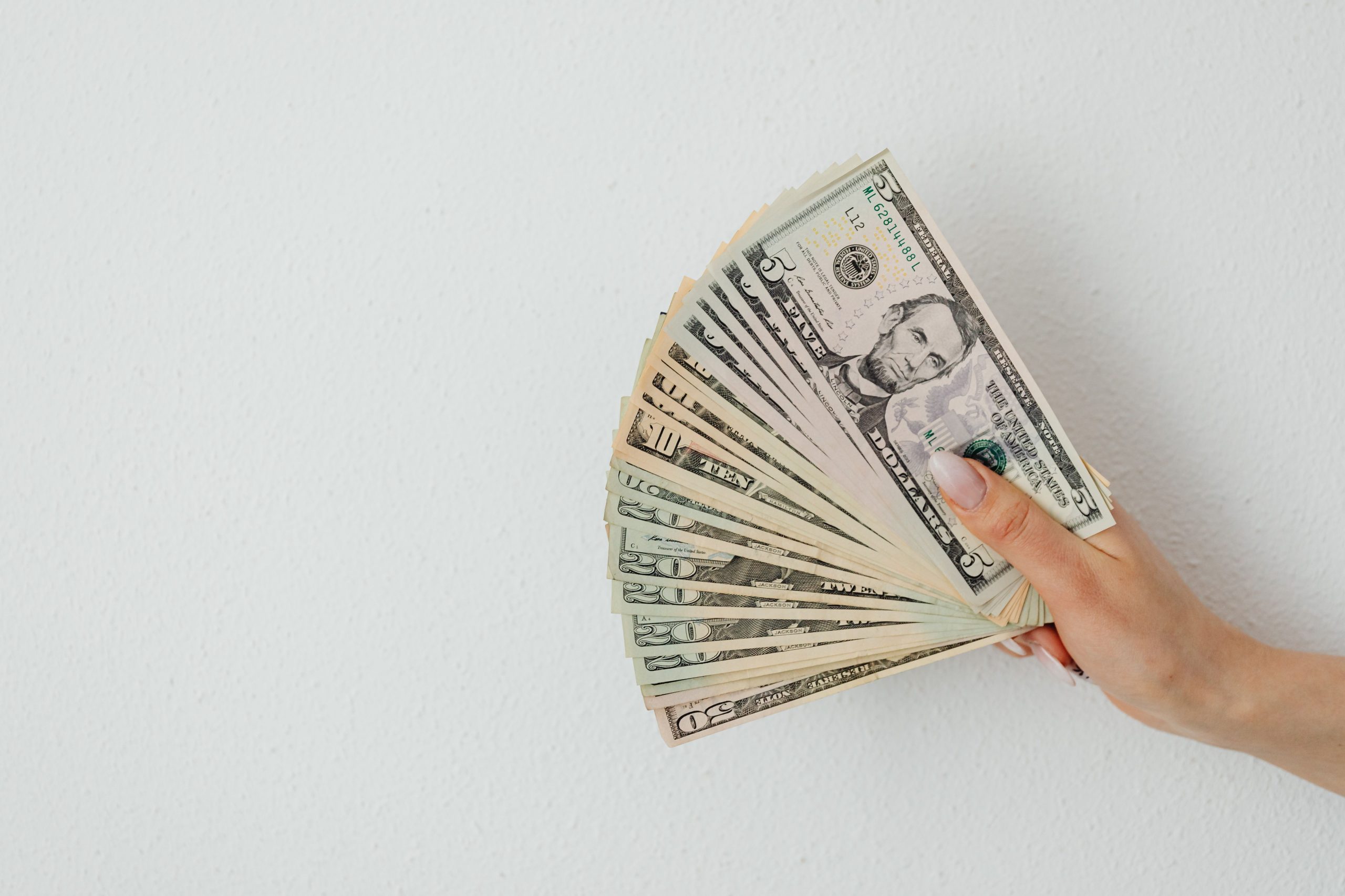 Main tenant plusieurs billets de dollars éventaillés