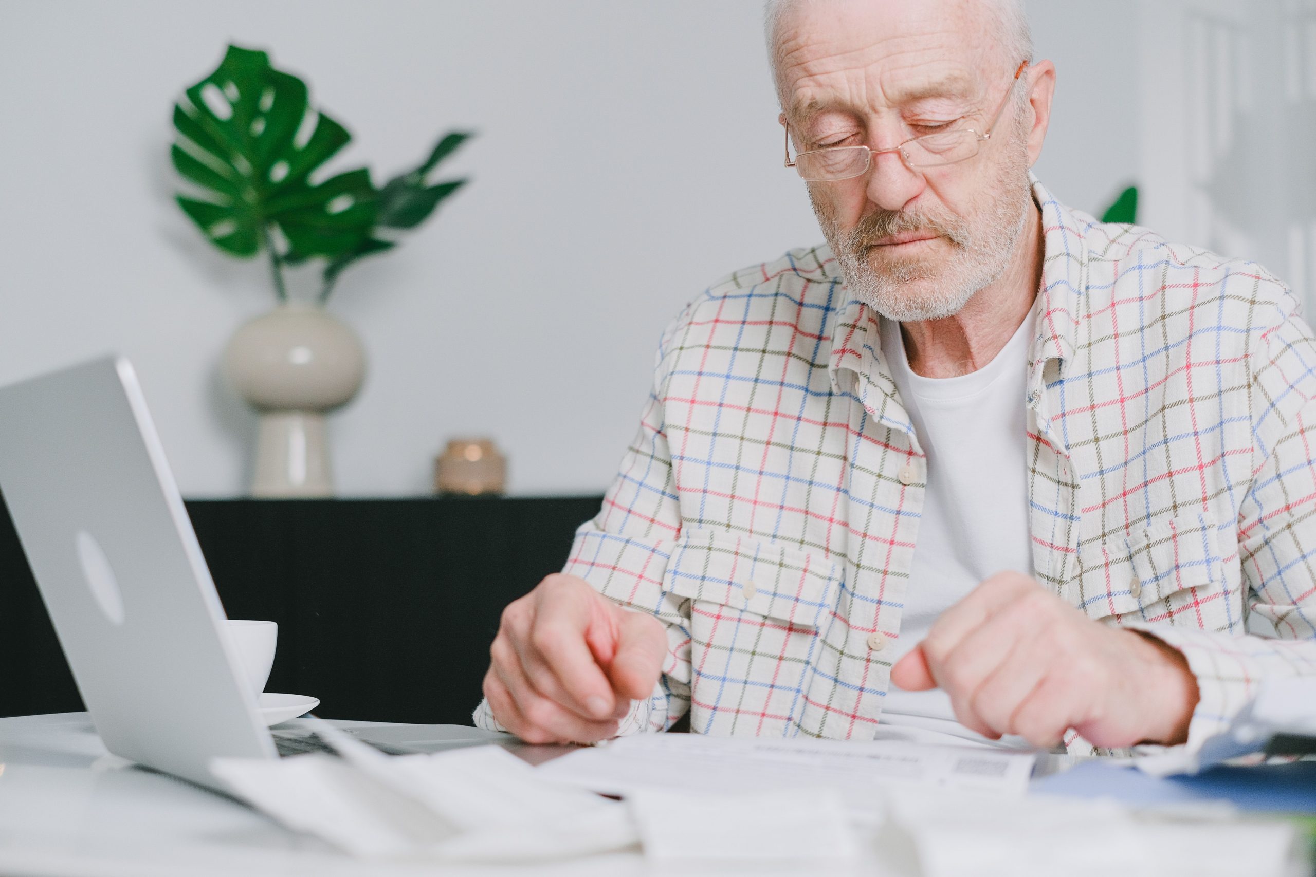Homme âgé lunettes travaille paperasse ordinateur